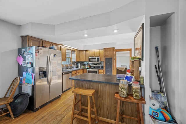 132 Middle School Dr, Saint Croix Falls, WI 54024 - kitchen featuring appliances with stainless steel finishes, a peninsula, light wood finished floors, a sink, and dark countertops