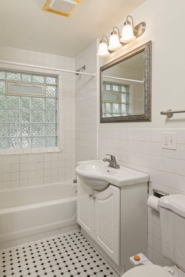3225 Hennepin Ave, Minneapolis, MN 55408 - bathroom with tile walls, toilet, vanity, tile patterned flooring, and shower / bathtub combination