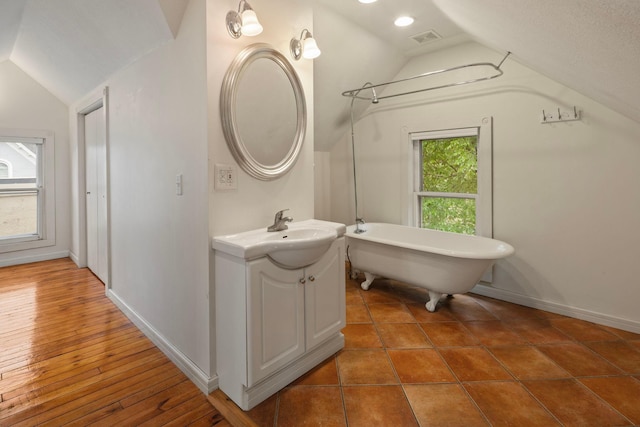 3225 Hennepin Ave, Minneapolis, MN 55408 - full bath with vaulted ceiling, a freestanding tub, vanity, and baseboards