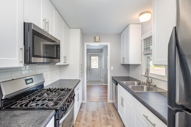 3101 Texas Ave S, Saint Louis Park, MN 55426 - kitchen with stainless steel appliances, dark countertops, white cabinets, light wood-type flooring, and backsplash