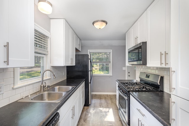3101 Texas Ave S, Saint Louis Park, MN 55426 - kitchen featuring stainless steel appliances, dark countertops, light wood finished floors, white cabinetry, and decorative backsplash