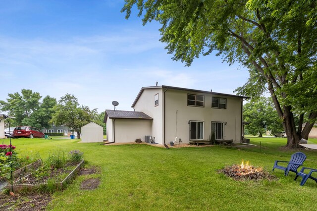 902 Ridge Dr SE, Saint Michael, MN 55376 - back of house featuring a storage unit, a fire pit, a lawn, stucco siding, and a garden