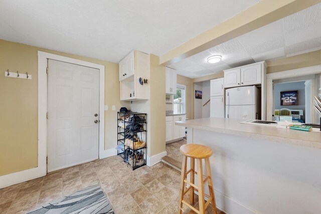 1039 9th Ave SW, Faribault, MN 55021 - kitchen featuring freestanding refrigerator, a kitchen breakfast bar, baseboards, white cabinetry, and light countertops