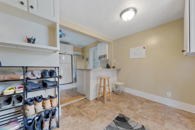1039 9th Ave SW, Faribault, MN 55021 - kitchen with freestanding refrigerator, white cabinets, a peninsula, baseboards, and a breakfast bar area