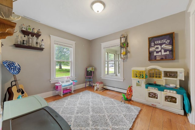 1039 9th Ave SW, Faribault, MN 55021 - recreation room with wood finished floors, baseboard heating, and baseboards