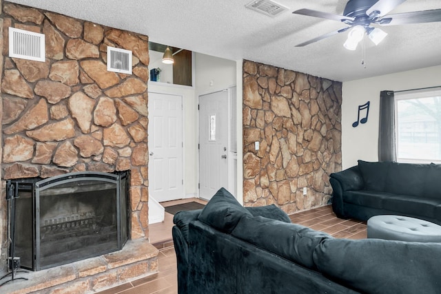 495 Saint Anthony Ave, Saint Paul, MN 55103 - living room with wood finish floors, a textured ceiling, a stone fireplace, and ceiling fan