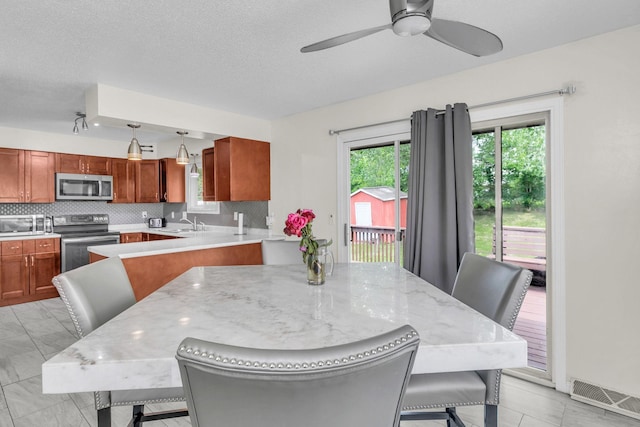 495 Saint Anthony Ave, Saint Paul, MN 55103 - kitchen featuring stainless steel appliances, backsplash, a ceiling fan, brown cabinetry, and a textured ceiling