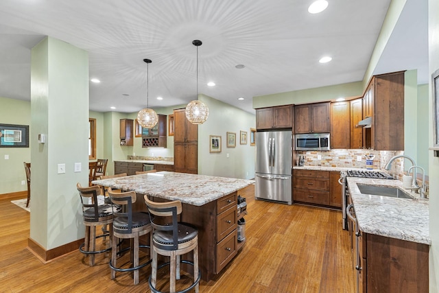 10390 Fenner Ave SE, Franklin Twp, MN 55328 - kitchen featuring stainless steel appliances, wood finished floors, a sink, light stone counters, and a kitchen bar