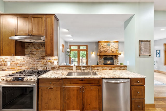 10390 Fenner Ave SE, Franklin Twp, MN 55328 - kitchen featuring appliances with stainless steel finishes, a sink, under cabinet range hood, baseboards, and light stone countertops