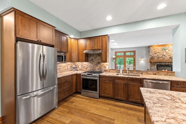 10390 Fenner Ave SE, Franklin Twp, MN 55328 - kitchen featuring appliances with stainless steel finishes, a sink, light wood-type flooring, decorative backsplash, and under cabinet range hood