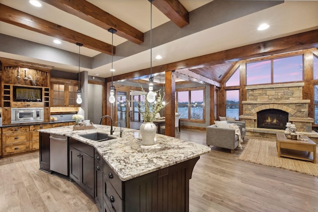 9328 Rhoy Ave, Chaska, MN 55318 - kitchen featuring stainless steel dishwasher, a sink, a center island with sink, light wood-style floors, and decorative light fixtures