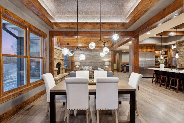 9328 Rhoy Ave, Chaska, MN 55318 - dining area featuring light wood-style floors, a stone fireplace, and a raised ceiling