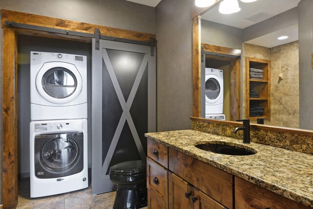 9328 Rhoy Ave, Chaska, MN 55318 - laundry room featuring stacked washing machine and dryer, a barn door, and stone finish floors