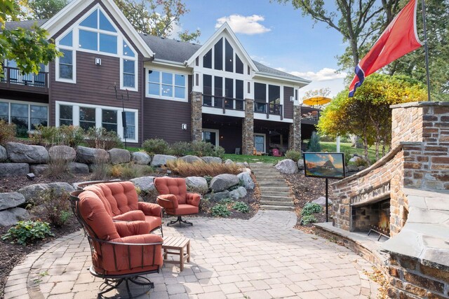 9328 Rhoy Ave, Chaska, MN 55318 - back of house with an outdoor stone fireplace, stairs, a patio area, and a sunroom