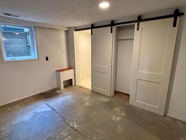 1116 Whitford St, Fergus Falls, MN 56537 - unfurnished bedroom with concrete flooring, a barn door, and a textured ceiling
