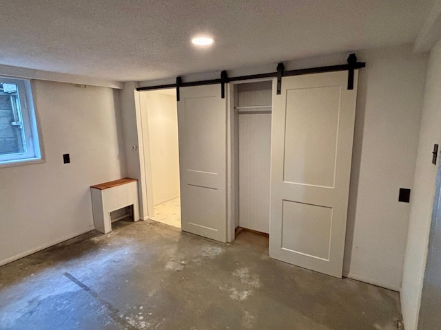 1116 Whitford St, Fergus Falls, MN 56537 - unfurnished bedroom with unfinished concrete floors, a barn door, a textured ceiling, and recessed lighting