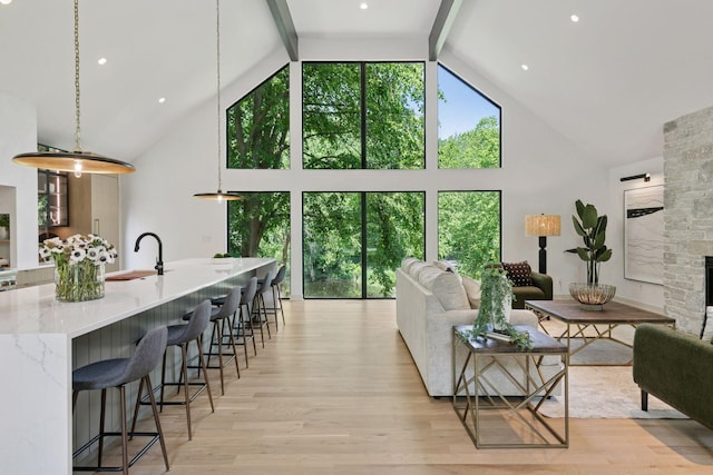 6608 Pawnee Rd, Edina, MN 55439 - living room with high vaulted ceiling, light wood-style flooring, beam ceiling, and a stone fireplace