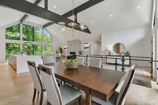 6608 Pawnee Rd, Edina, MN 55439 - dining space with high vaulted ceiling, beam ceiling, light wood-type flooring, and a large fireplace