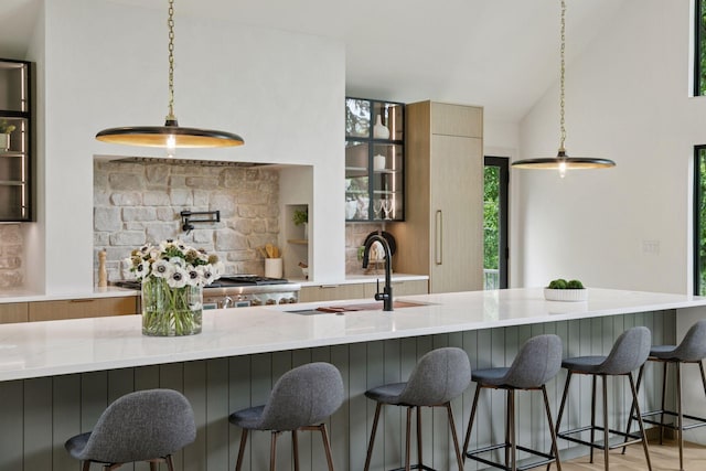 6608 Pawnee Rd, Edina, MN 55439 - kitchen with modern cabinets, glass insert cabinets, pendant lighting, vaulted ceiling, and light stone countertops