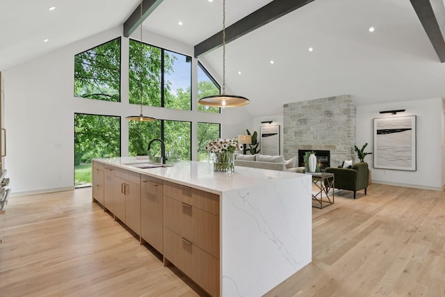 6608 Pawnee Rd, Edina, MN 55439 - kitchen with high vaulted ceiling, beam ceiling, modern cabinets, light stone counters, and light brown cabinetry