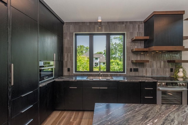 19923 See Gull Rd, Brainerd, MN 56401 - kitchen with appliances with stainless steel finishes, custom range hood, backsplash, a sink, and dark cabinetry
