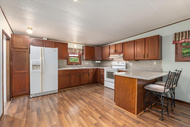 W7324 State Road 65, Trimbelle, WI 54003 - kitchen featuring white appliances, under cabinet range hood, a peninsula, wood finished floors, and backsplash