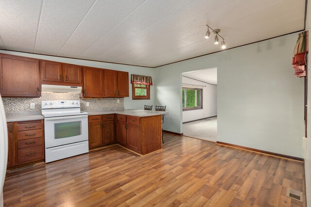 W7324 State Road 65, Trimbelle, WI 54003 - kitchen with under cabinet range hood, white electric range, a peninsula, and light countertops