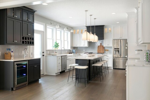 6501 Timber Arch Dr, Chaska, MN 55318 - kitchen featuring stainless steel appliances, wine cooler, a sink, a kitchen island, and wood finished floors