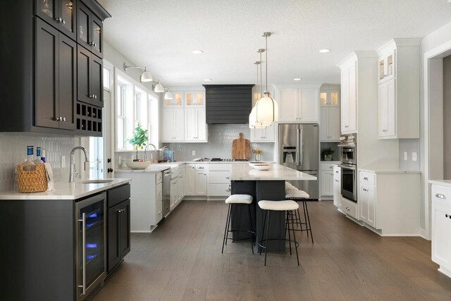 6501 Timber Arch Dr, Chaska, MN 55318 - kitchen with stainless steel appliances, a sink, beverage cooler, a breakfast bar area, and dark wood finished floors