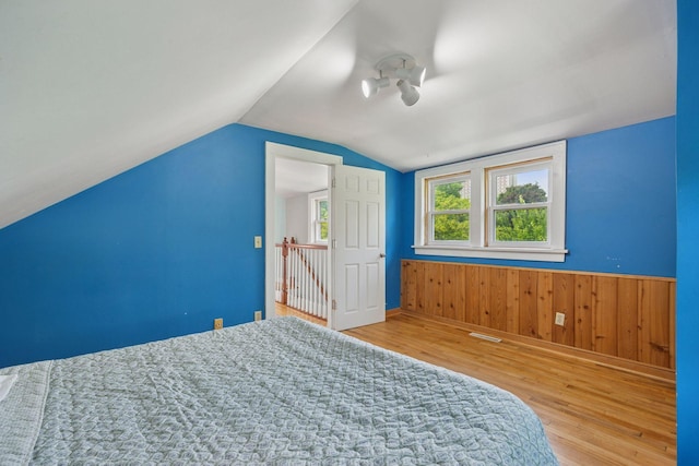 3015 22nd St, Minneapolis, MN 55406 - bedroom featuring wood finished floors, vaulted ceiling, wood walls, and a wainscoted wall