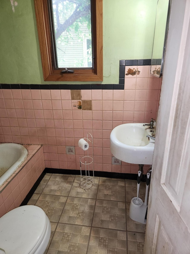 1816 Malvern St, Lauderdale, MN 55113 - bathroom with tile walls, a sink, toilet, a tub to relax in, and wainscoting