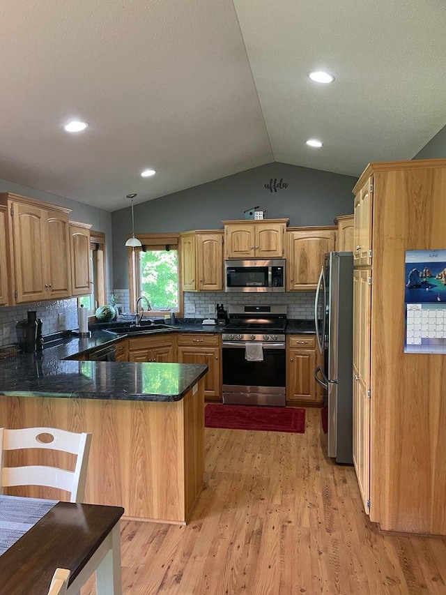 409 Iris Ln NE, Saint Joseph, MN 56374 - kitchen featuring appliances with stainless steel finishes, a peninsula, lofted ceiling, decorative backsplash, and light wood-style flooring