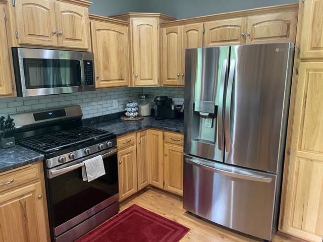 409 Iris Ln NE, Saint Joseph, MN 56374 - kitchen with appliances with stainless steel finishes, light brown cabinets, light wood-style flooring, and backsplash