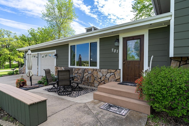 701 Mill St, Fertile, MN 56540 - view of exterior entry with stone siding, driveway, a garage, outdoor dining area, and a patio