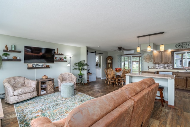 701 Mill St, Fertile, MN 56540 - living area featuring a barn door, dark wood finished floors, a textured ceiling, ceiling fan, and a wall unit AC