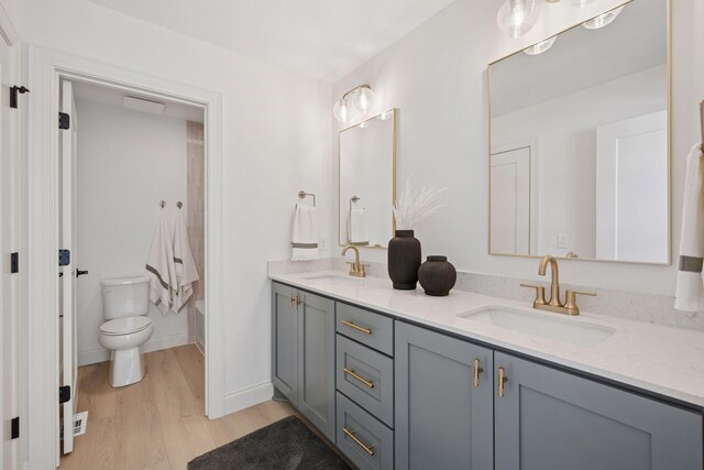 10154 Peony Ln N, Maple Grove, MN 55311 - full bathroom with double vanity, wood finished floors, toilet,  shower combination, and baseboards
