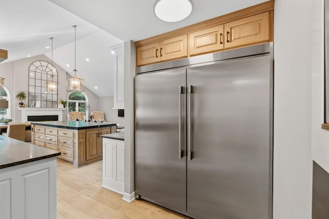 6141 Sherman Cir, Edina, MN 55436 - kitchen with built in fridge, light wood-style flooring, lofted ceiling, dark stone counters, and hanging light fixtures