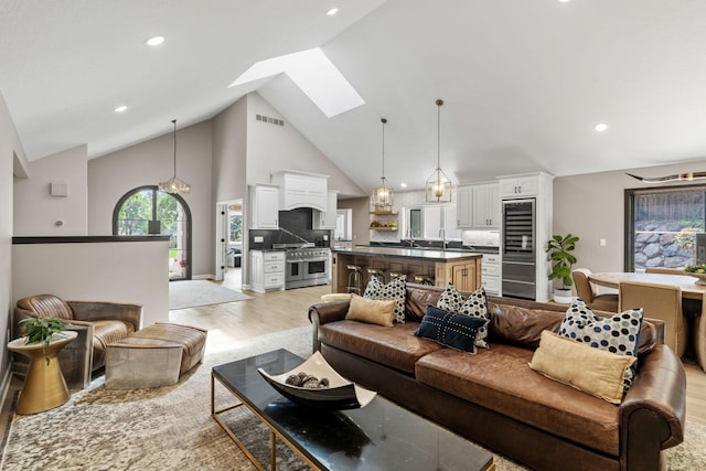 6141 Sherman Cir, Edina, MN 55436 - living room featuring a skylight, high vaulted ceiling, light wood-style flooring, recessed lighting, and wine cooler