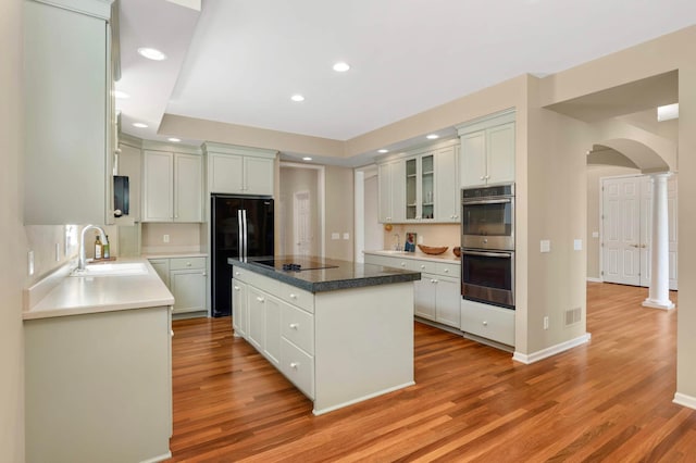 1540 Waterford Ct, Golden Valley, MN 55422 - kitchen with black appliances, arched walkways, a sink, a kitchen island, and light wood finished floors