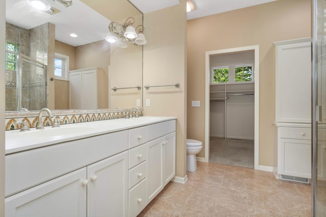 1540 Waterford Ct, Golden Valley, MN 55422 - bathroom featuring double vanity, toilet, tiled shower, baseboards, and a spacious closet