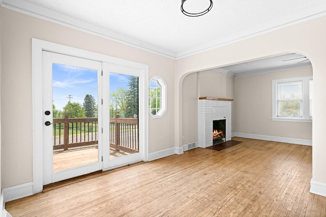 804 20th Ave E, Duluth, MN 55812 - unfurnished living room featuring a fireplace, wood finished floors, arched walkways, crown molding, and baseboards