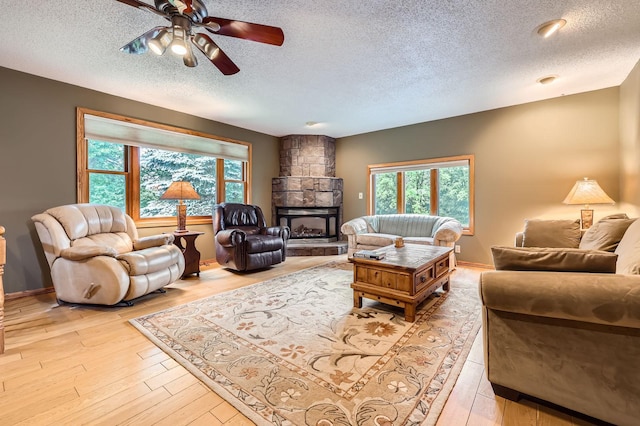 5959 373rd St, North Branch, MN 55056 - living room featuring a textured ceiling, a ceiling fan, light wood-style floors, and a stone fireplace