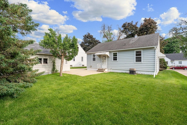 1306 6th Ave NW, Austin, MN 55912 - back of property featuring a lawn, a patio area, a chimney, and a shingled roof