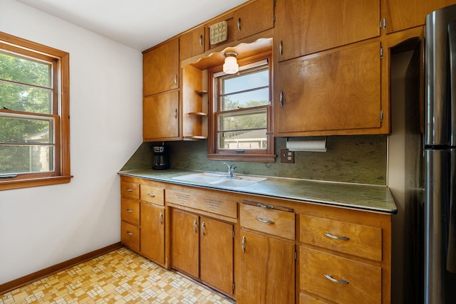 1306 6th Ave NW, Austin, MN 55912 - kitchen with freestanding refrigerator, decorative backsplash, brown cabinets, and plenty of natural light