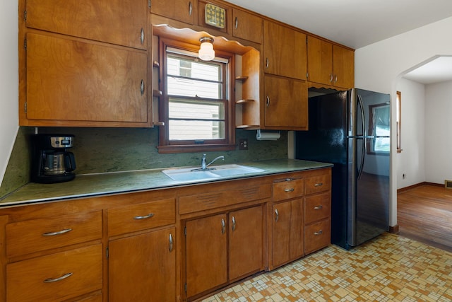 1306 6th Ave NW, Austin, MN 55912 - kitchen featuring freestanding refrigerator, brown cabinets, and backsplash