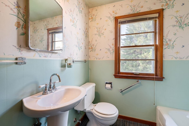1306 6th Ave NW, Austin, MN 55912 - full bathroom featuring a tub, wainscoting, wallpapered walls, and tile walls