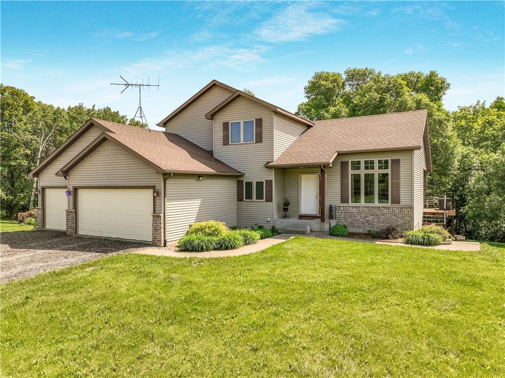 75 County Road F, Troy Twp, WI 54022 - traditional-style house featuring an attached garage, gravel driveway, a front yard, and a shingled roof