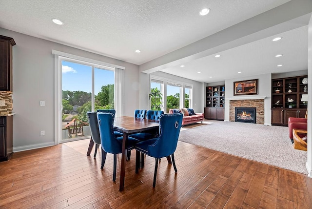 10388 188th St W, Lakeville, MN 55044 - dining room featuring hardwood / wood-style flooring, a glass covered fireplace, baseboards, a textured ceiling, and recessed lighting
