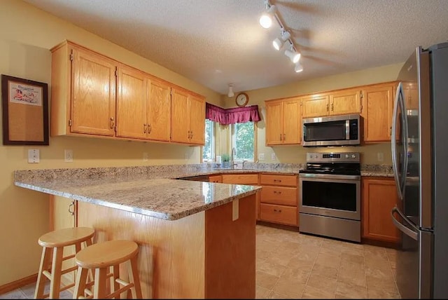 23501 Birch Cir, Rogers, MN 55374 - kitchen featuring stainless steel appliances, a peninsula, light stone countertops, a kitchen breakfast bar, and a textured ceiling
