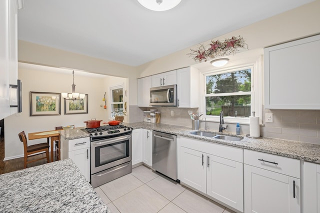 179 County Road F W, Shoreview, MN 55126 - kitchen with stainless steel appliances, white cabinets, decorative backsplash, a chandelier, and light stone countertops